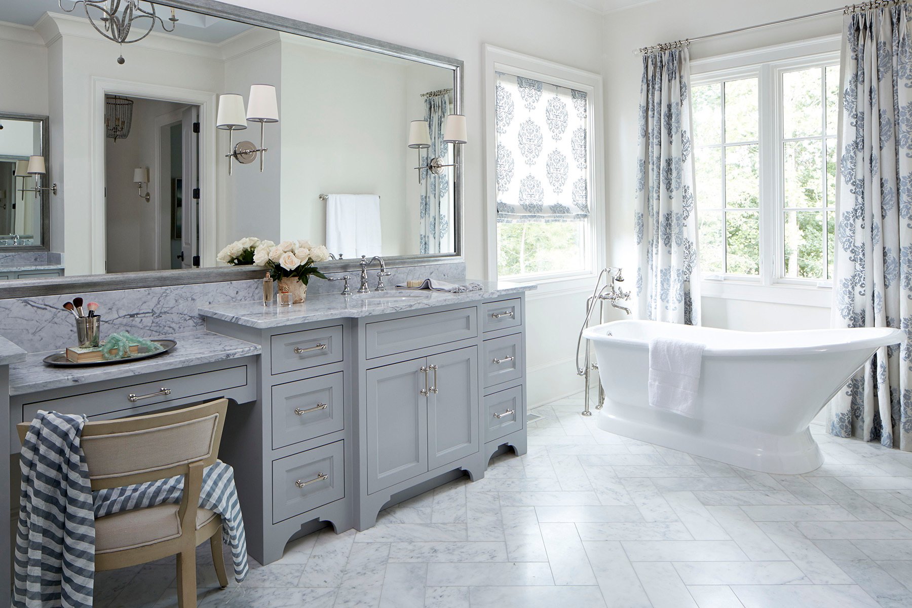 beautiful bright bathroom with marble, gray shaker style cabinetry, a soaking tub & white windows.