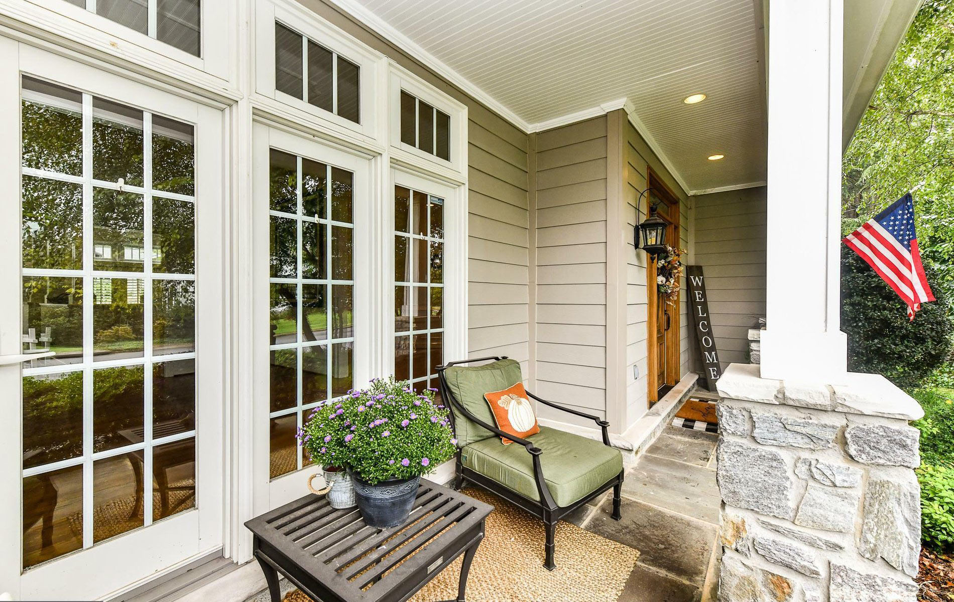 Traditional porch with white frame windows and doors. stone flooring and columns. 