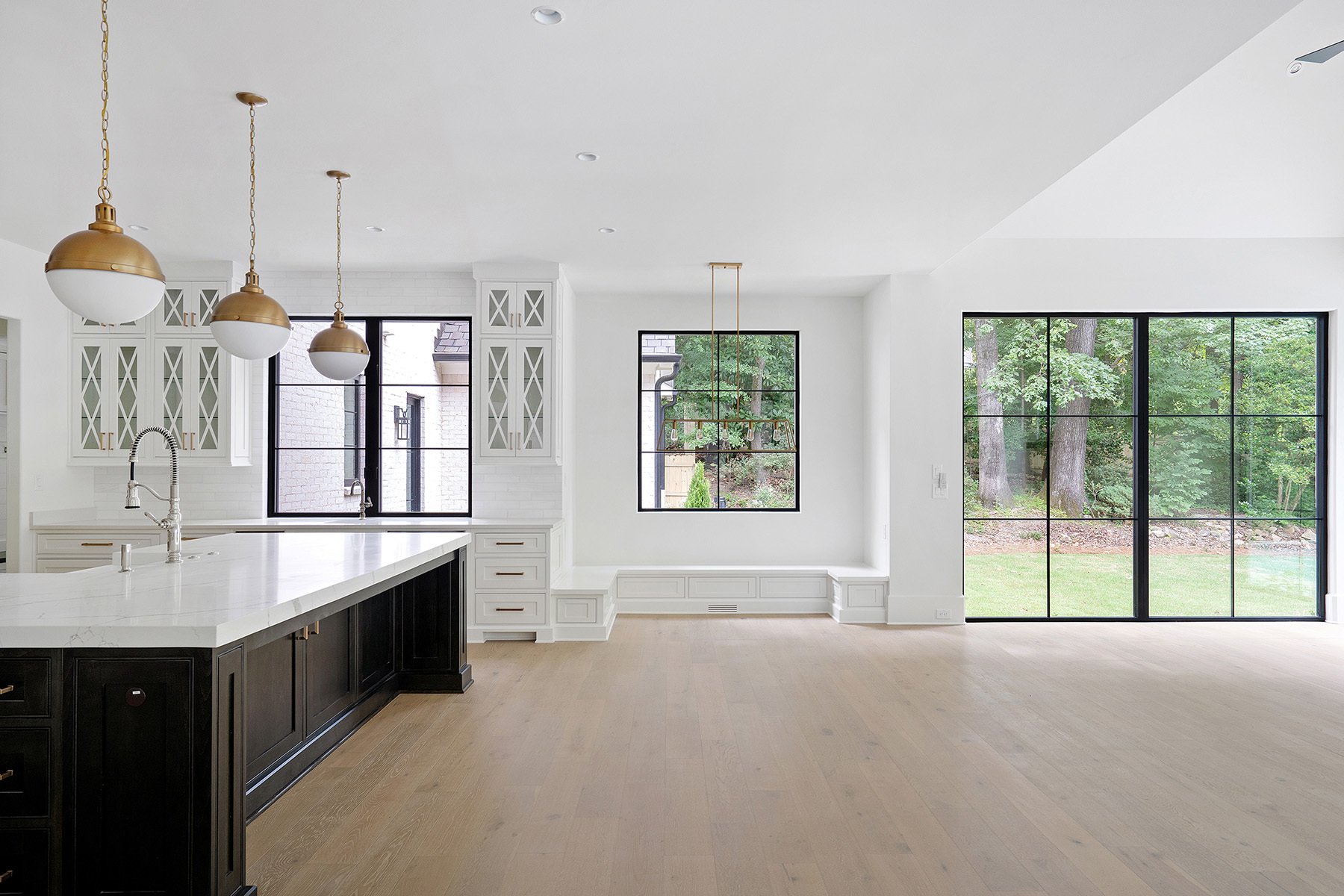 Inside view of a home with thin black frame windows. Black kitchen island.