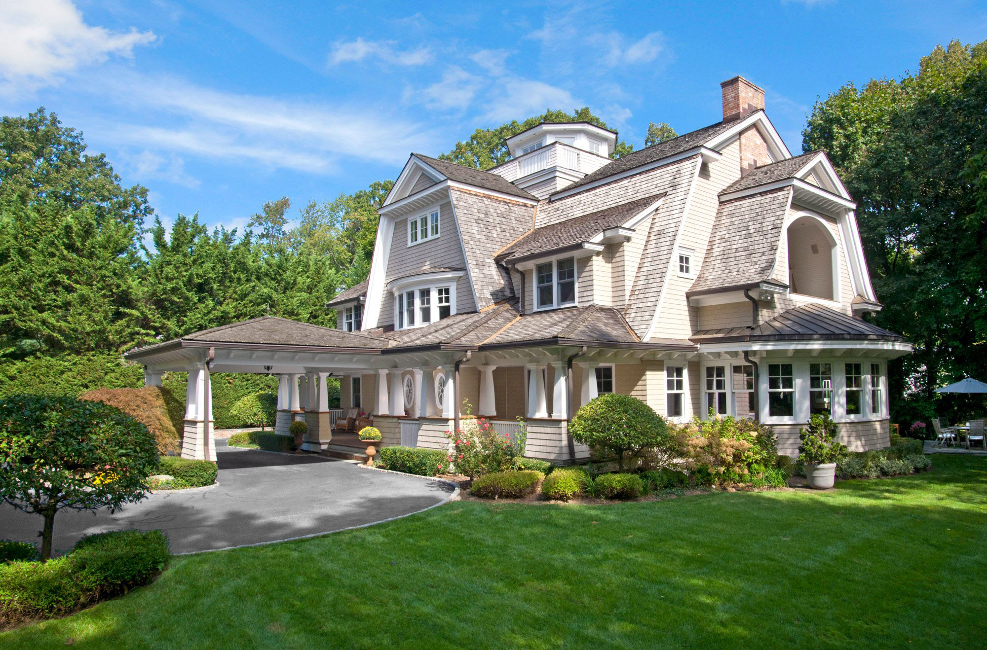 Beautiful shingle style home with a concrete driveway colored dark grey.