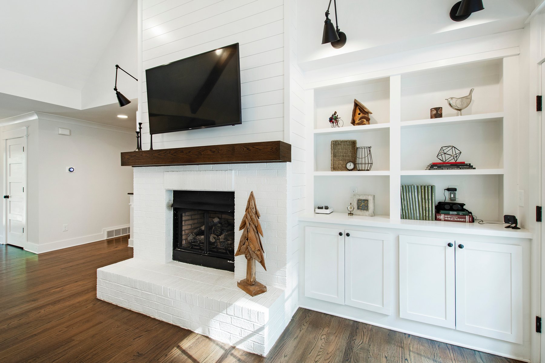 red brick fireplace painted white with built in cabinets, wood mantle and wood floors Farmhouse style