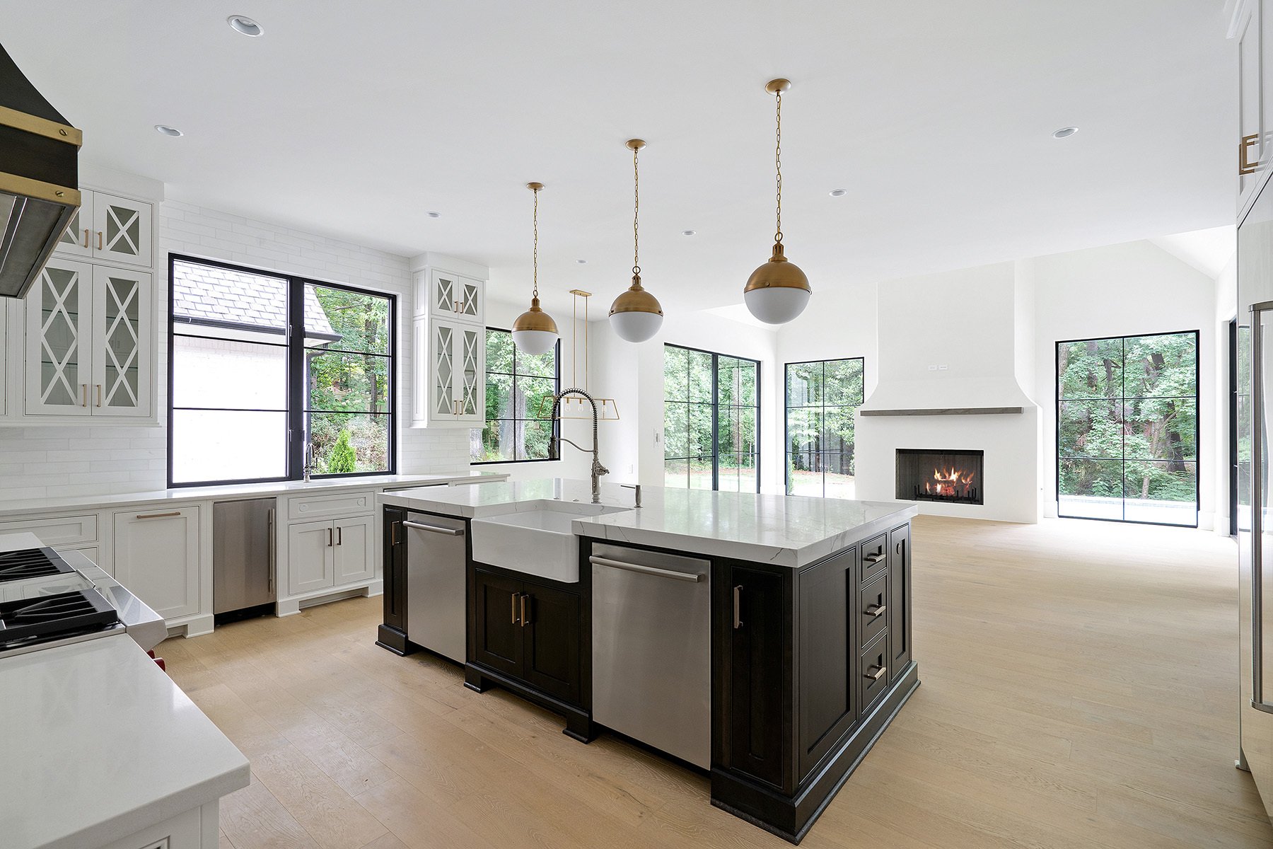 Beautiful black island with white cabinetry featuring a farmhouse sink and stainless steel appliances.