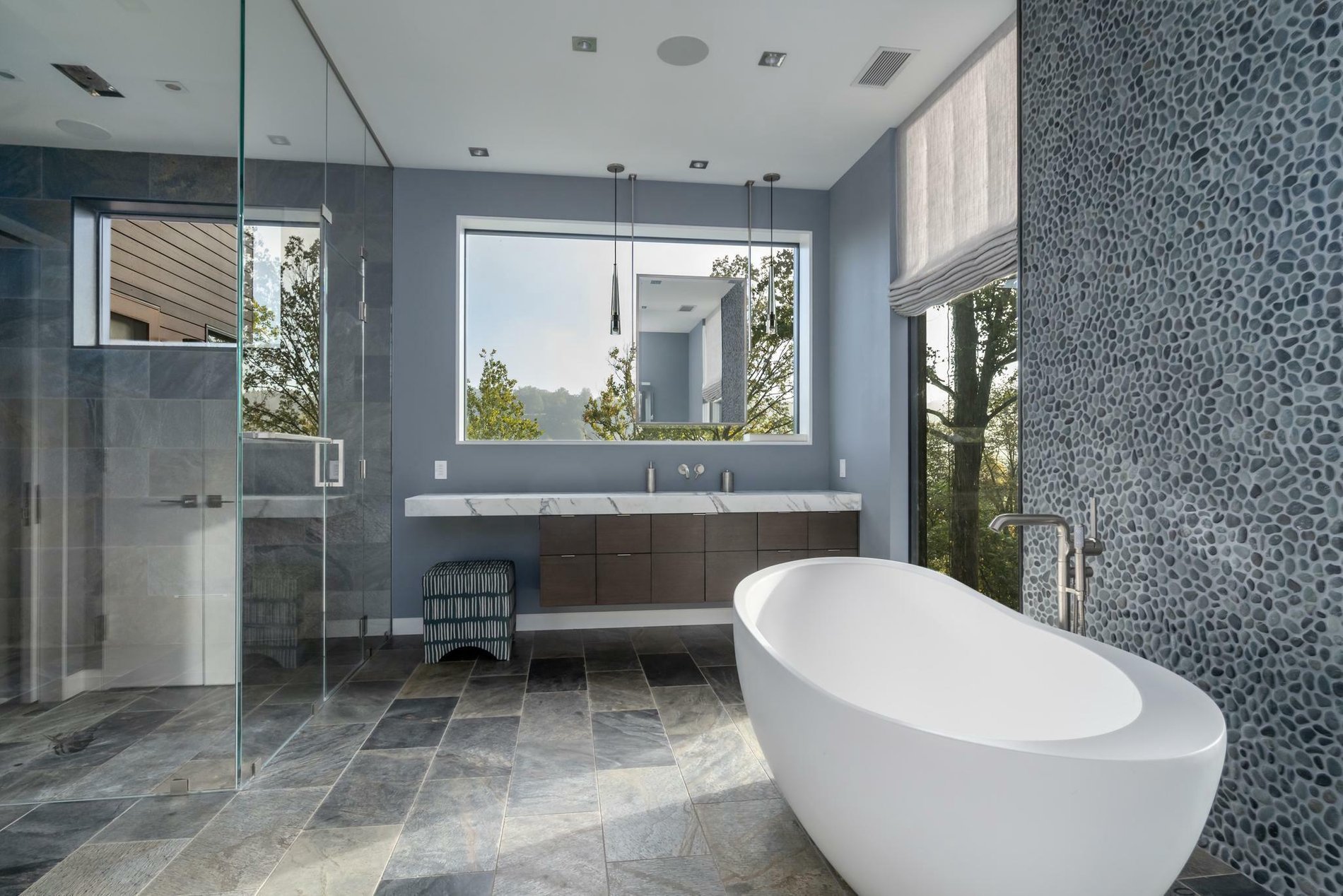 Custom bathroom with a roll-in shower, frameless glass doors and rain shower head.