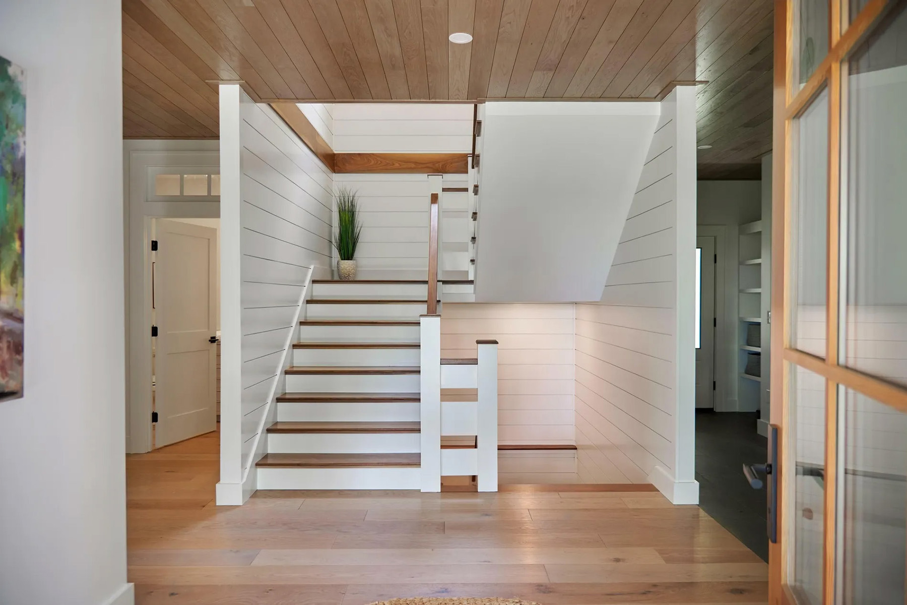 Tongue and Groove wood ceiling stained natural with recessed lighting and white shiplap walls. Matching wood floors and stairs.