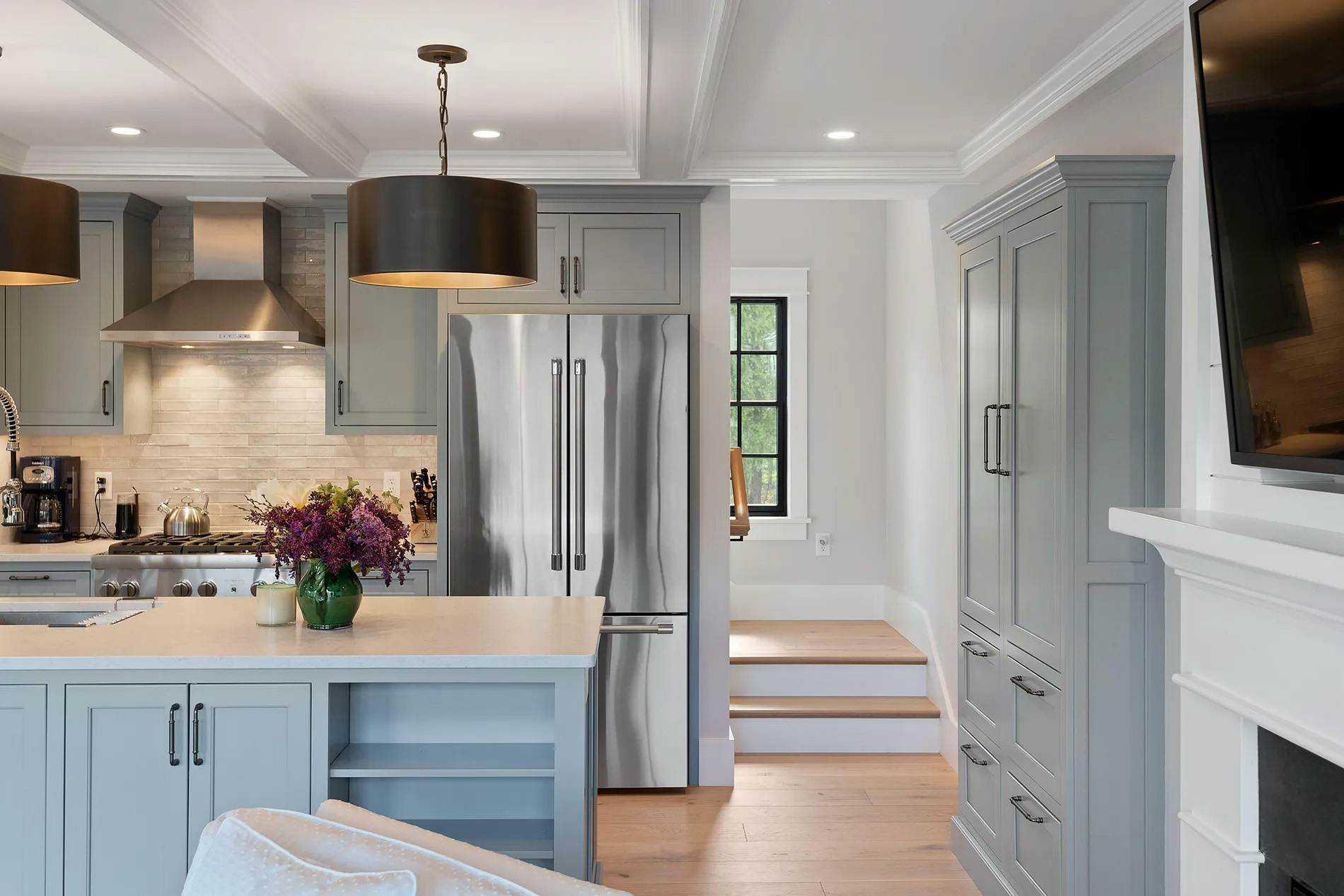 Beautiful galley style kitchen island with light blue-gray cabinetry.