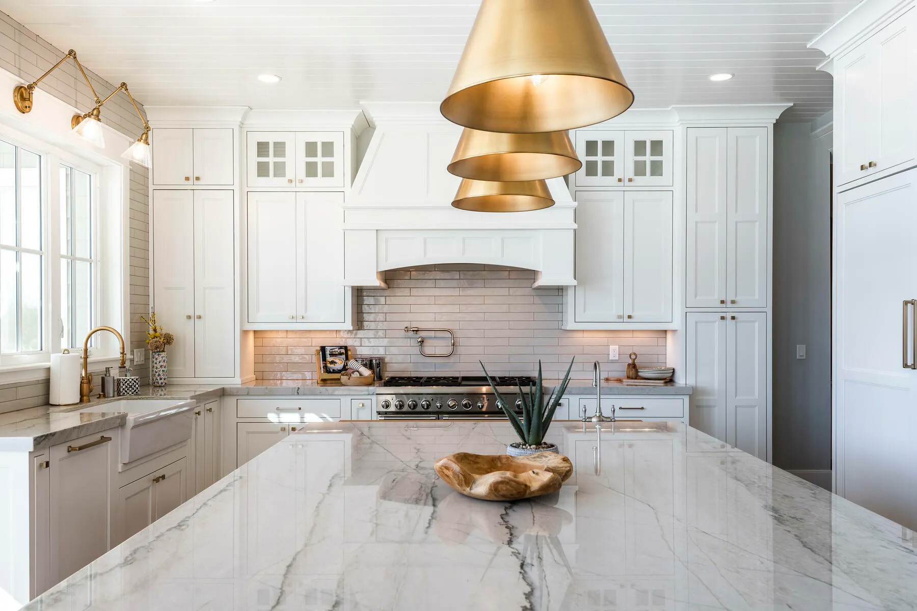Marble island countertop with three gold pendants.