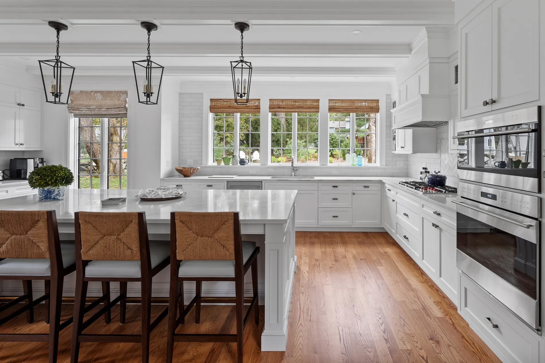 beautiful all white kitchen with island, wood floors, black pendants.