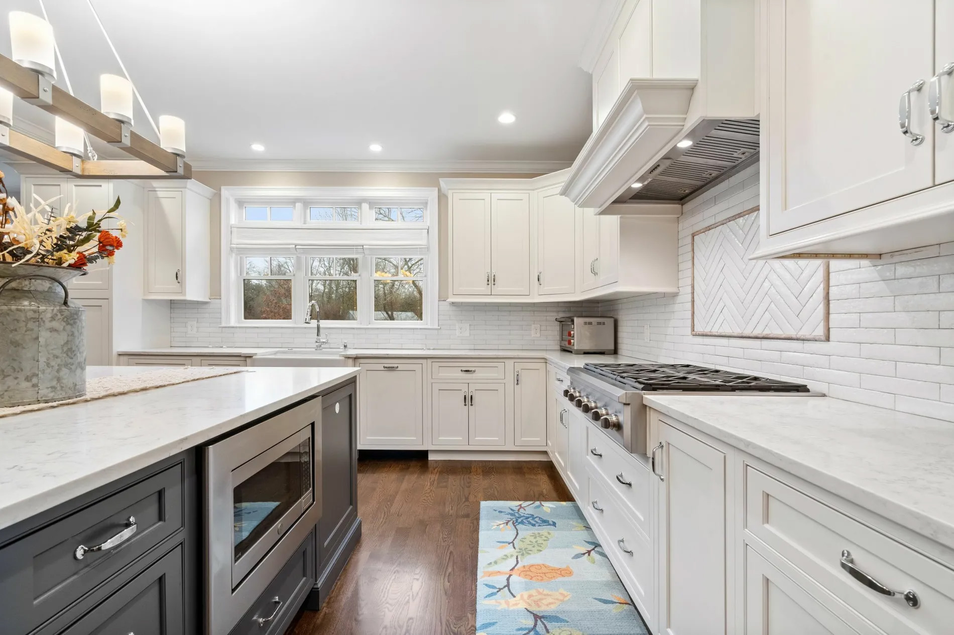 White wall cabinets with a blue-gray island. Built in stainless steel appliances.