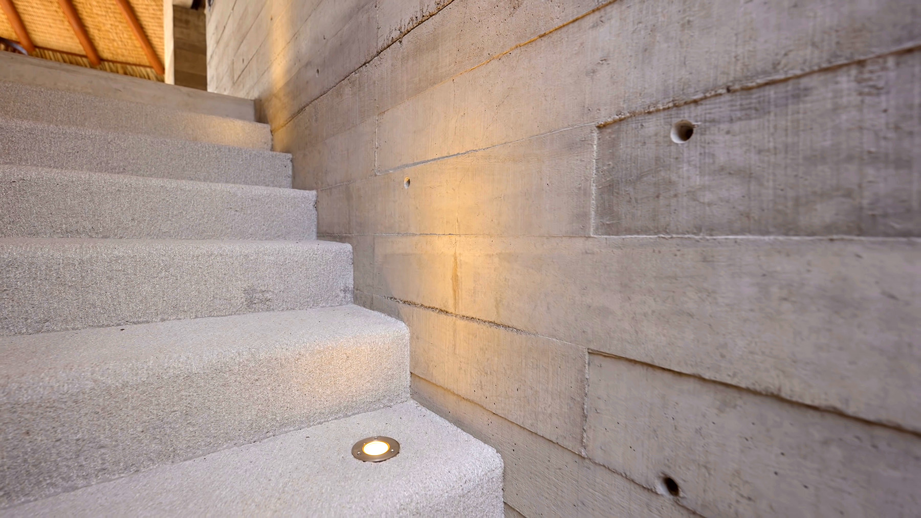 closeup view of board formed concrete walls next to concrete steps with step lighting