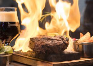 ribeye vs t-bone steak on an open flame with red wine