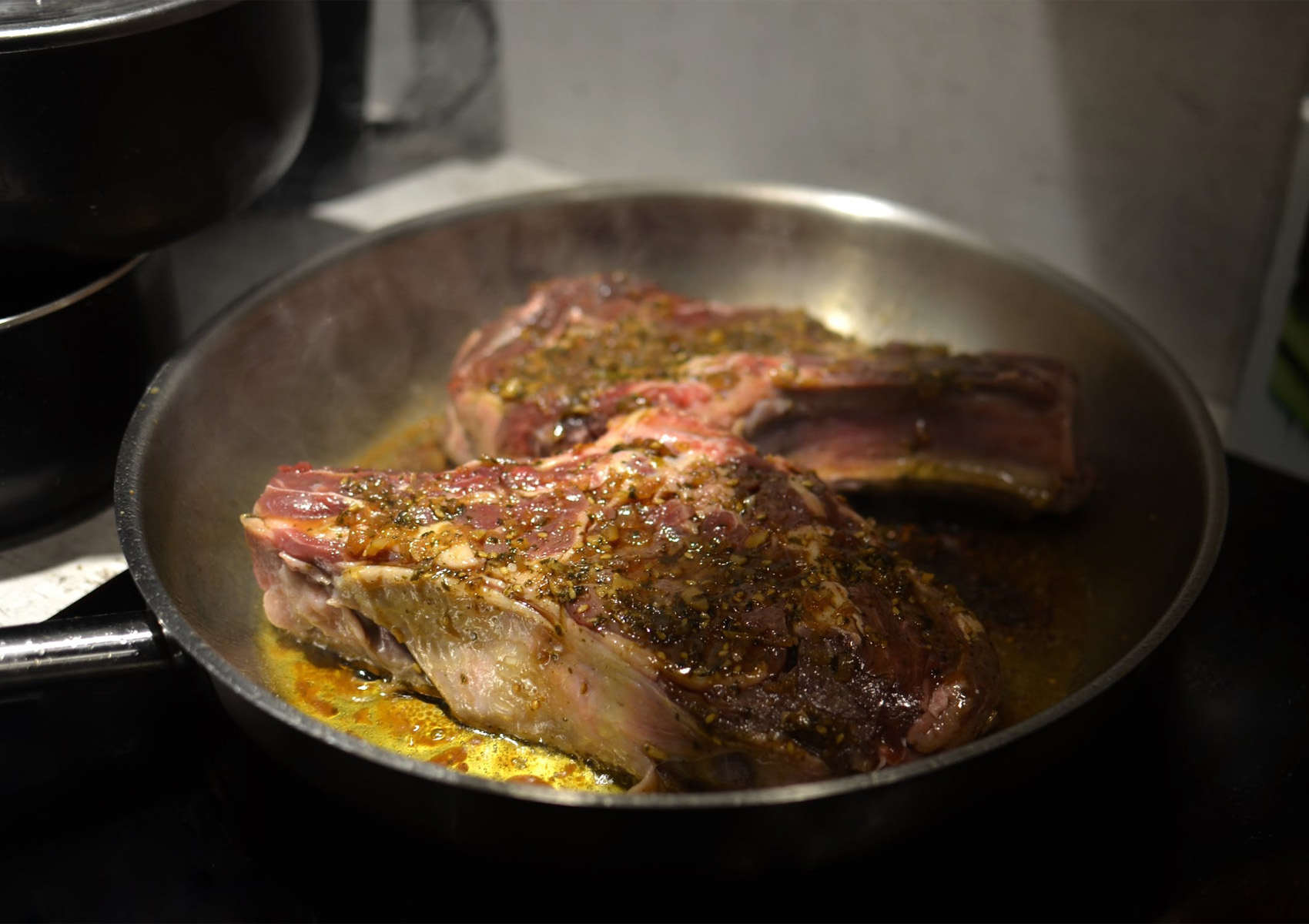 basting steak with butter and herbs in a hot skillet