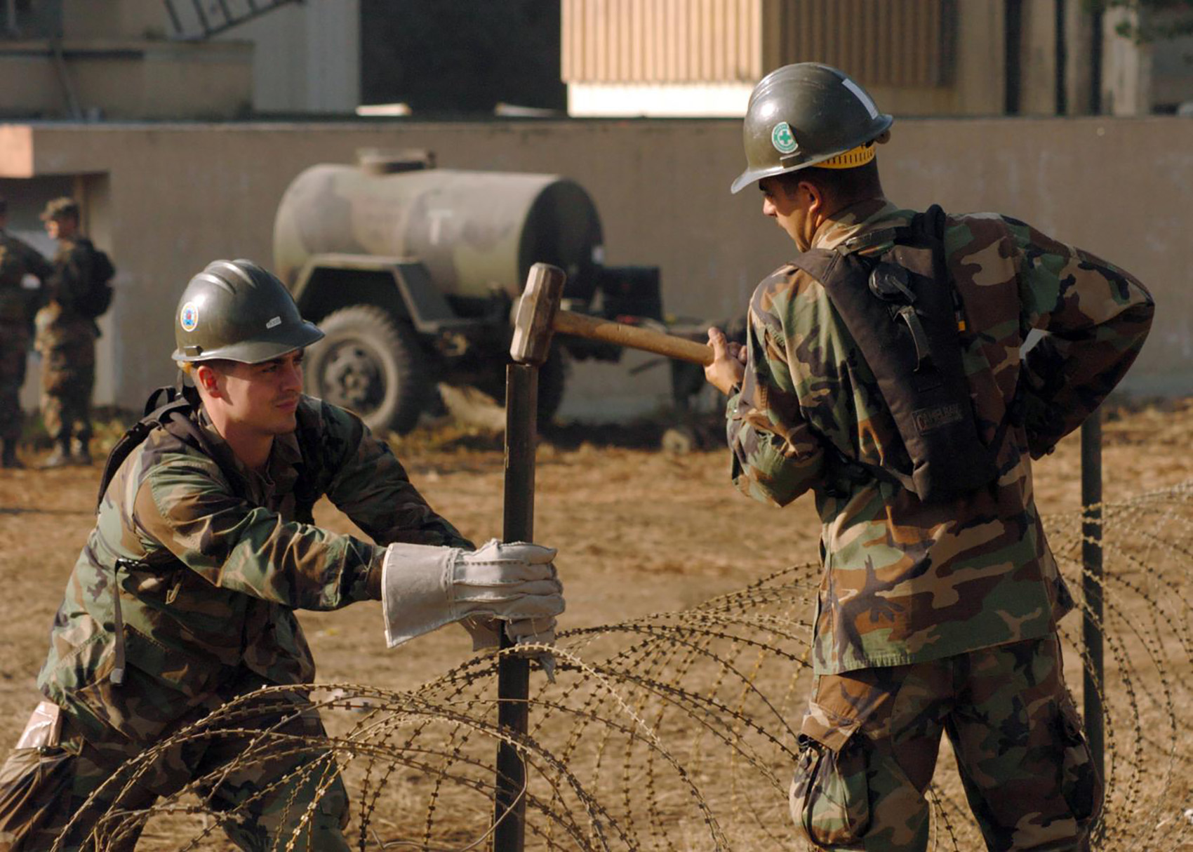 what are sledgehammers used for - navy using a sledge hammer to bang in metal fence spikes