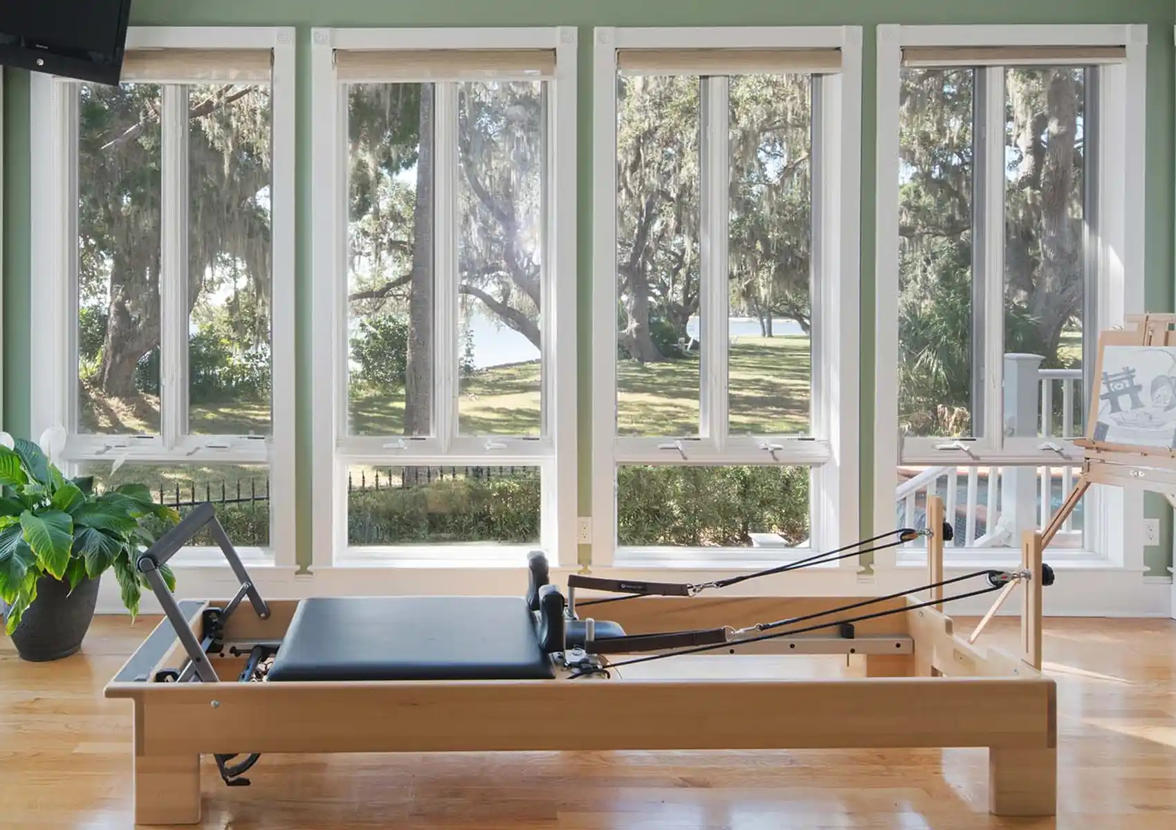 sunroom home gym, wood floors, exercise equipment, floor to ceiling windows, green walls