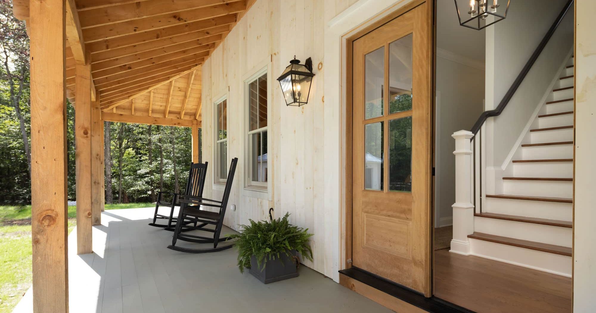 modern farmhouse wrap around front porch with exposed beams, natural wood vertical shiplap siding